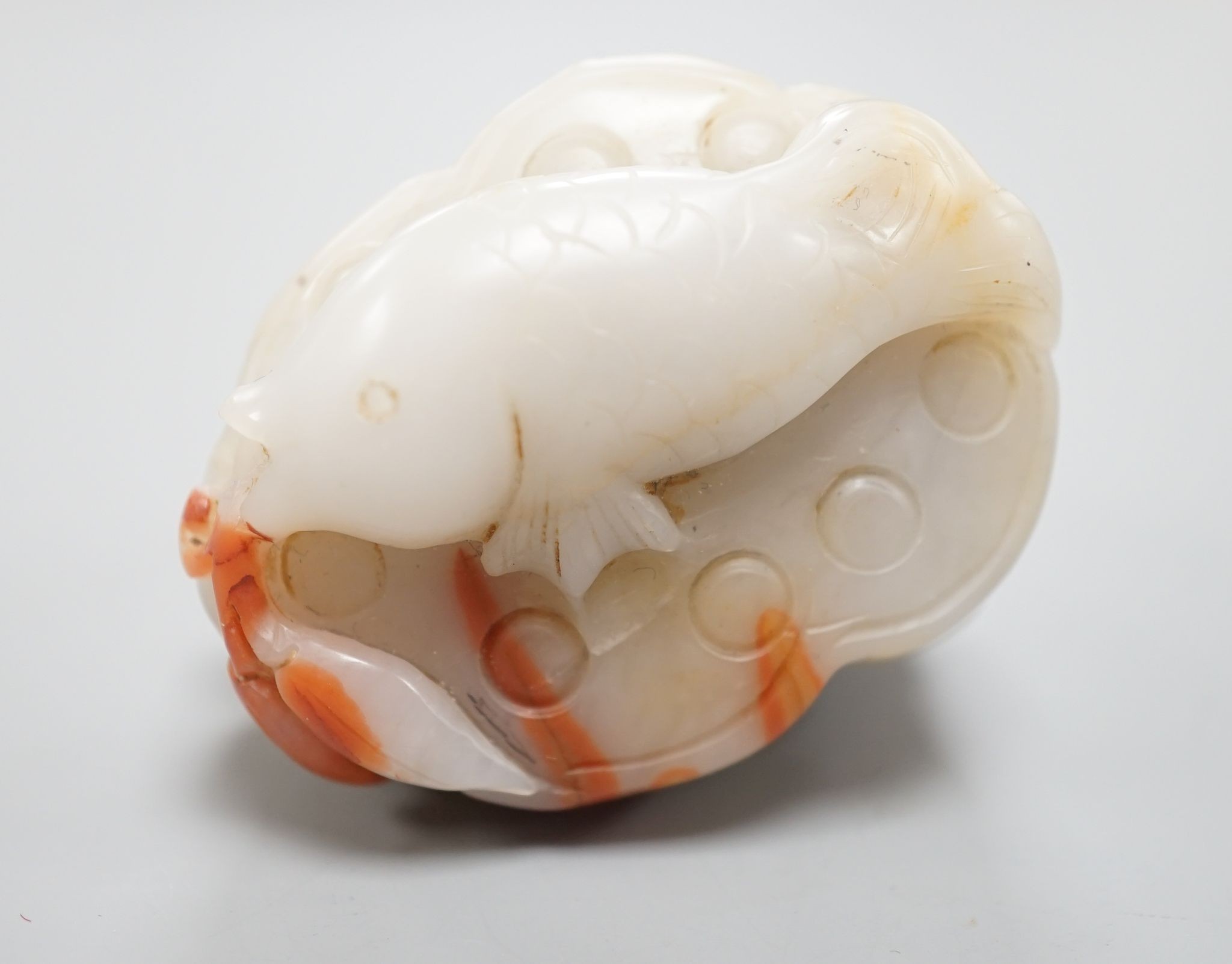 A Chinese pale celadon and russet jade 'lotus pod and fish' carving 6cm